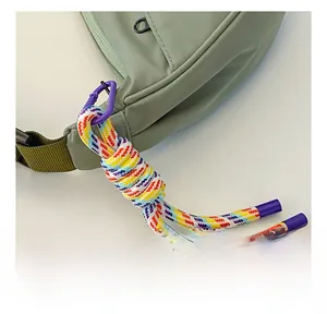 Detail of a smooth zipper on a pea green nylon bag with a colorful braided lanyard cord