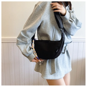 Detail of black crescent crossbody bag with colorful rope accent and Fashion label