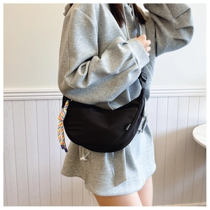 Close-up of black crescent nylon crossbody bag with fashion tag and woven rope detail