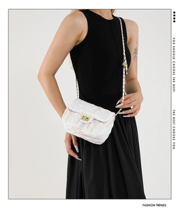 Detailed view of white quilted crossbody bag with colorful stitching and gold lock