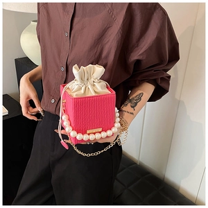 Dettaglio borsa a secchiello rosa con trama ondulata, manico di perle e catena d'oro