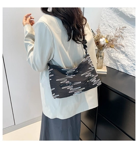 Detail of colorful wave embroidery and black bow drawstring on the crescent shoulder bag