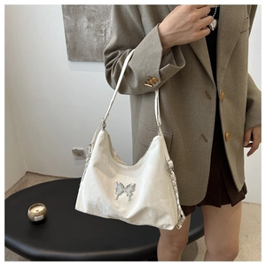 Detail of white PU leather bag with silver butterfly charm and chain shoulder strap