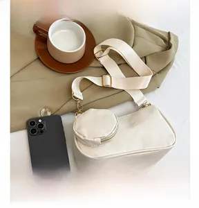 Detail view of cream shoulder bag with a round coin purse and golden hardware details