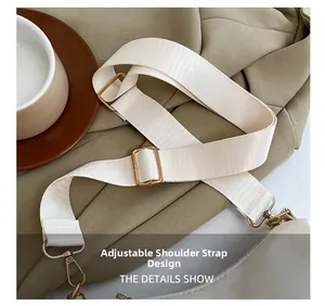 Detail showing adjustable beige nylon shoulder strap with premium gold metal buckles