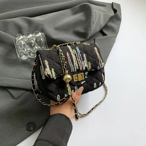 Quilted black crossbody bag with colorful woven texture and gold chain strap held by model