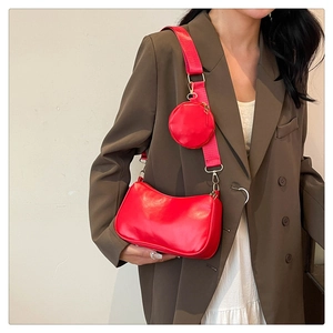 Detail of red baguette shoulder bag with wide strap and circular coin purse attachment