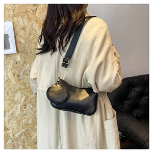 Detail of black leather shoulder bag with a woven strap and detachable round pouch charm
