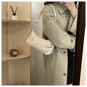 Dettaglio della borsa baguette beige con rivetti argentati e fibbia in metallo regolabile
