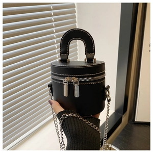 Macro view of black cylinder bucket bag with white contrast stitching and silver chain strap