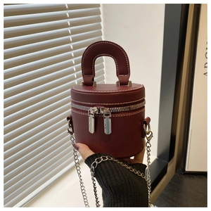 Detail view of burgundy cylindrical mini crossbody bag with white contrast stitching