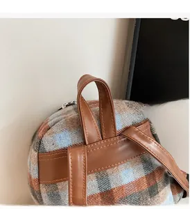 Detail of plaid fabric backpack with durable brown leather handle and neat stitching