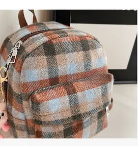 Close-up of retro plaid wool backpack with leather strap and pink plush charm detail