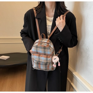 Detailansicht eines karierten Mini-Rucksacks mit Lederriemen und Plüschtier-Anhänger