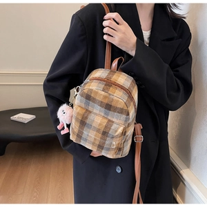 Close-up of vintage plaid mini backpack with leather straps and cute plush doll pendant