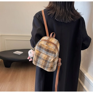 Detail view of mini plaid backpack with pink plush charm and brown leather straps