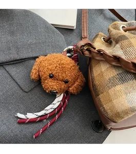 Gros plan d'une breloque en peluche ours brun avec corde tressée sur un sac à carreaux