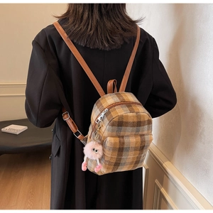 Detail eines karierten Mini-Rucksacks mit Plüsch-Anhänger und braunen Ledergurten