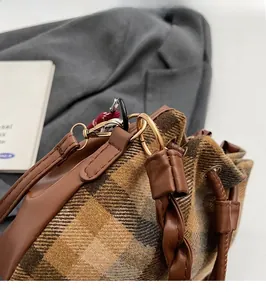 Gros plan du sac seau rétro en laine à carreaux avec ferrures dorées et cuir