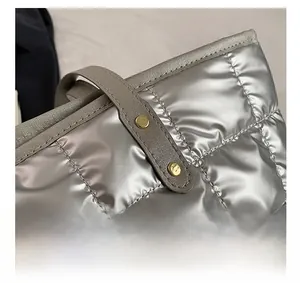 Detail of silver quilted tote bag featuring metallic texture and golden rivet accents