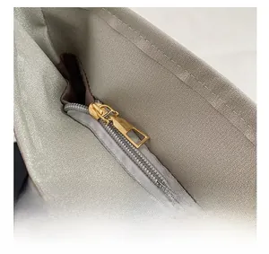 Detail showing the golden metal zipper closure on a light grey quilted down tote bag