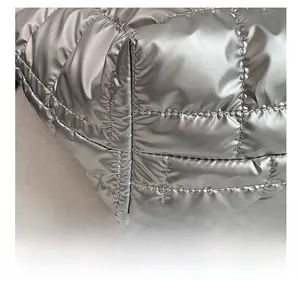 Detail shot of silver quilted puffer tote bag fabric showing precision stitching