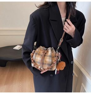 Detail of vintage plaid bucket bag with plush bear charm and woven handle detail