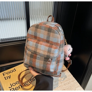 Detail eines Tweed-Rucksacks mit Vintage-Karomuster und Plüsch-Anhänger-Dekoration