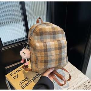 Detail of plaid backpack with wool fabric texture and pink plush toy charm accessory