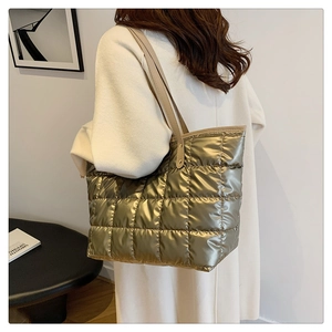 Detailed view of the large gold quilted tote bag with square stitching and leather straps