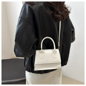 Minimalist white leather crossbody bag shown on person with black leather jacket