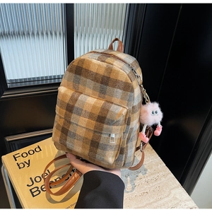 Detail eines Vintage-Karo-Minirucksacks aus Wollstoff mit rosa Plüsch-Anhänger