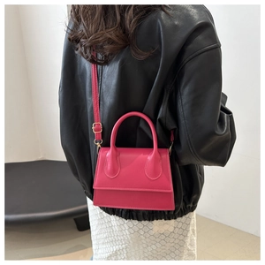 Hot pink mini crossbody bag styled with black leather jacket in a fashion street view