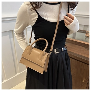 Stylishly minimalist mini crossbody bag in khaki synthetic leather worn by a model