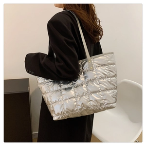 Detail of silver metallic quilted tote bag with padded texture and slim handles