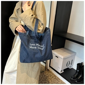 Borsa tote in denim blu con testo Less Mondays More Sundays indossata a spalla
