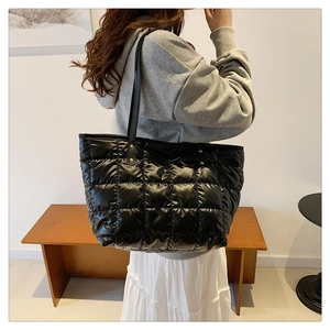 Large black quilted down tote bag with square stitching and leather straps for winter