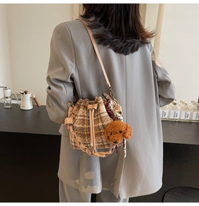 Détail d'un sac seau en laine à carreaux marron avec peluche et foulard en soie imprimé
