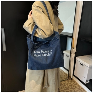 Détail du grand sac cabas en denim bleu foncé avec imprimé texte blanc artistique