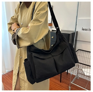 Detail of black canvas tote bag with large front pockets and adjustable wide strap