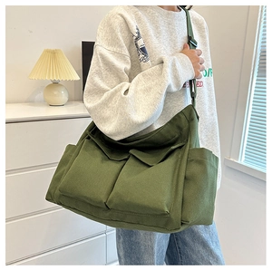 Detail of army green canvas tote bag with double front flap pockets and adjustable strap