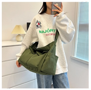 Detail of army green canvas tote bag showing multiple functional pockets and wide strap