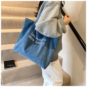 Dettaglio della borsa tote in denim blu con ricamo 'Less Mondays More Sundays' sul tessuto