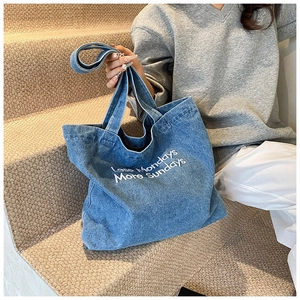 Dettaglio della borsa tote in denim blu con ricamo bianco Less Mondays More Sundays