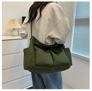 Model wearing a large military green canvas tote bag with functional utility pockets