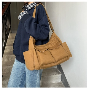 Close-up of brown canvas tote bag with multi-pocket utility design and wide shoulder strap