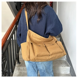 Detailed side view of a large khaki canvas tote bag worn on shoulder in a casual setting