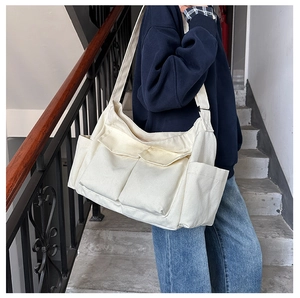 Detail showing multi-pocket canvas tote bag with adjustable wide shoulder strap