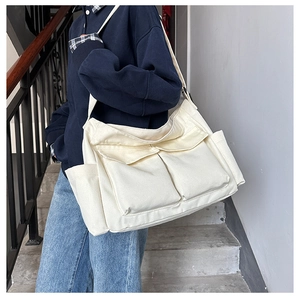 Detail view of cream canvas tote bag with front flap pockets and adjustable strap
