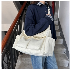 Detailed side view of beige canvas messenger bag with large front flap pockets and wide strap